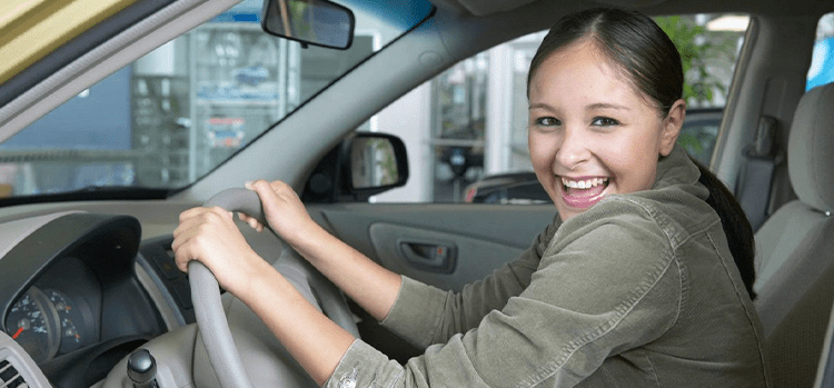 A woman sitting in the drivers seat of her car.