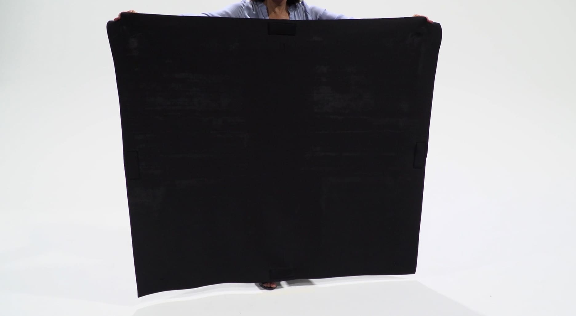 A person holding up a black blanket