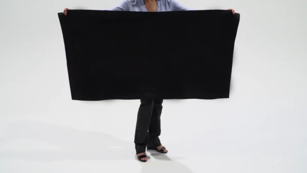 A person holding a large black board in front of their face.